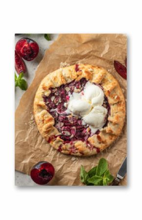 Galette or pie with plums and almonds served with ice cream scoops on parchment paper background top view. Summer traditional homemade sweet pastries