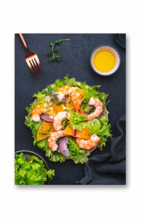 Juicy shrimp salad with orange, lettuce, red onion with olive oil and juice dressing, black background, top view