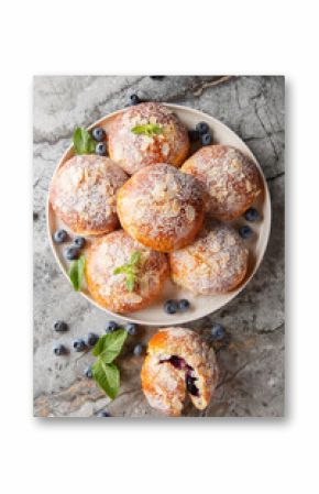 Traditional brioche buns with blueberry filling closeup on the plate on the table. Vertical top view from above