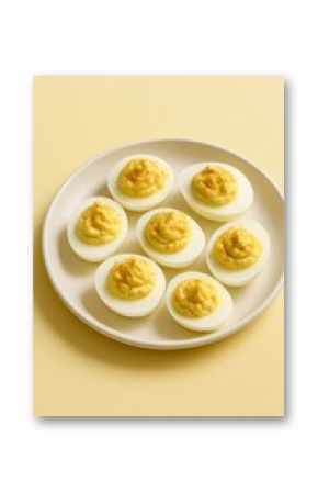 Traditional deviled eggs served on a white plate with pastel yellow background — classic American appetizer with creamy yolk filling, minimalist food presentation