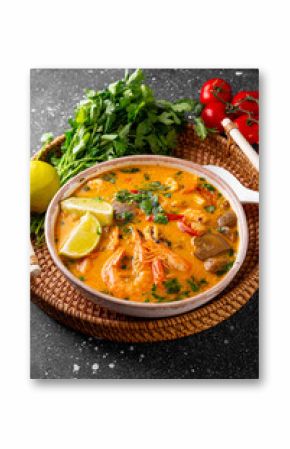 Tom yum soup with shrimp, sea food and lime on dark background vertical photo