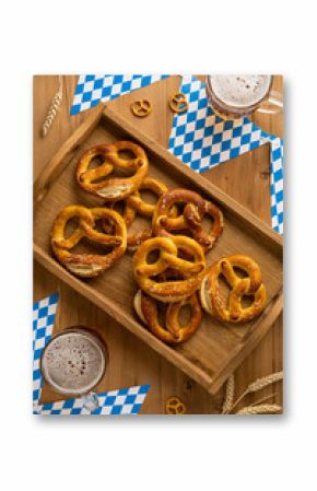 A flatlay top vertical view tray filled with salted pretzels alongside beer mugs set on Bavarian-themed decor