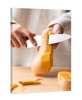 Woman hand holding kitchen knife and peeling butternut squash, Homemade cooking