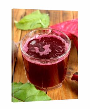 There is a glass of freshly squeezed beetroot juice on the wooden table.