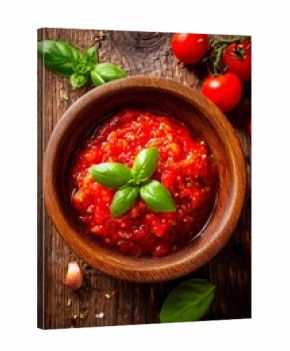 A vibrant tomato sauce crafted from ripe tomatoes, fresh basil, and garlic is presented in a rustic wooden bowl. Surrounding ingredients enhance the natural flavors