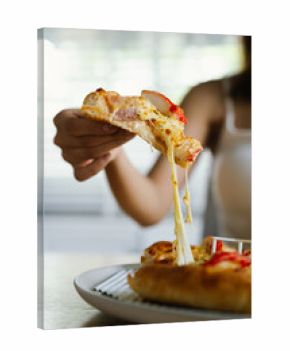 woman enjoys a freshly baked pizza with cheese, crab sticks and pineapple on a wooden table, ready to be served.