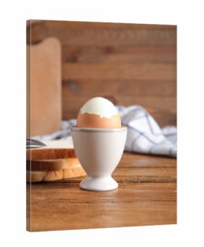 Holder with boiled chicken egg on wooden background
