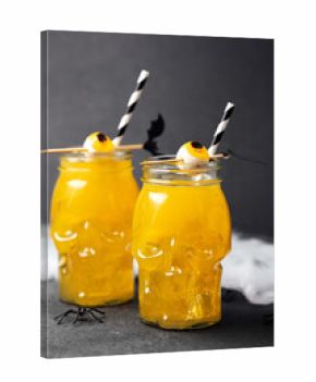 Two Halloween drinks in skull glasses with eyeball garnishes and striped straws