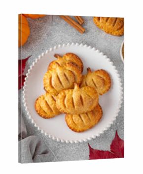 Pumpkin mini pies or hand pies with glass of coffee on a stone background. Traditional autumn dessert for Halloween and Thanksgiving. Copy space