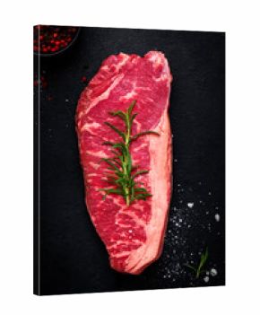 Delicious raw picanha beef steak from marbled beef with a fat cushion from the rump cut with rosemary and pepper, black background. top view