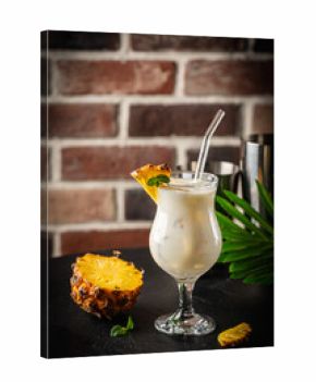 Traditional caribbean summer Pina Colada cocktail with rum, coconut milk and pineapple garnish on black background
