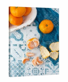 Top View of Tangerines in a White Bowl on Blue and White Tile Background  One Tangerine Out of Bowl on Blue Cloth  One Tangerine Peeled