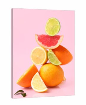 Tower made of different cut citrus fruits with leaves on pink background