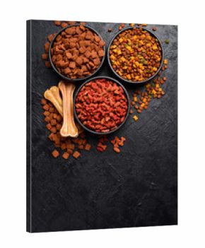 Assortment of dry food for pets. On a black stone background. Free space for text.