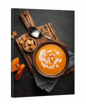 Creamy pumpkin soup served in a bowl, garnished with crunchy croutons and a swirl of dairy cream, ideal for autumn top view