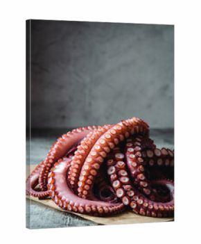 Fresh octopus tentacles arranged on rustic wooden board for cooking prep
