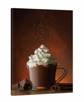 Grated chocolate pouring into cup of hot chocolate with whipped cream against brown background