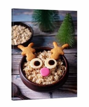 Oatmeal in a bowl in the form of reindeer for Christmas holidays on a wood background