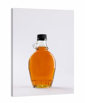 Vertical image of glass bottle of maple syrup on white background, with copy space
