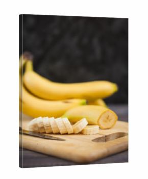 sliced banana with a knife on wooden board