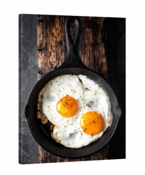 fried eggs in black skillet top view with space for a text