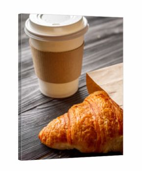 cup coffee and croissant in paper bag on wooden background