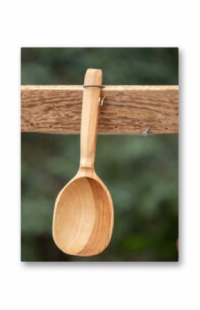 A wooden spoon is hanging from a wooden post