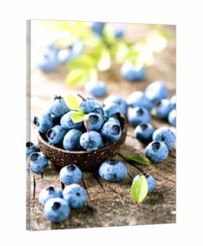 Organic blueberries with green leaves over rustic wooden table