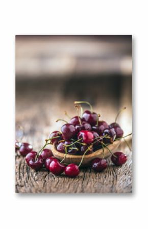 Cherries. Fresh sweet cherries. Delicious cherries with water drops in retro bowl on old oak table.