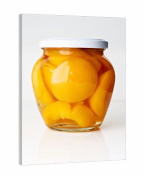 Canned peaches in glass jar isolated on white background