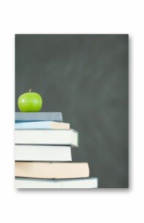 Green apple in front of blackboard on books