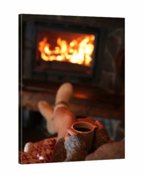 Woman resting with cup of hot drink near fireplace