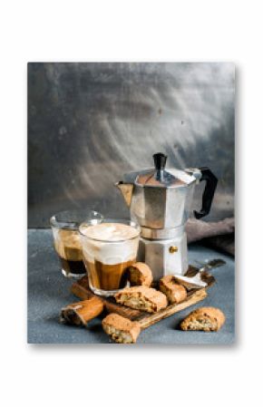 Glass of latte coffee on rustic wooden board, cantucci biscuits and steel Italian Moka pot, grey background