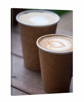 Two cups of latte art with heart shape in brown paper cup. selective focus