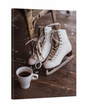 A pair of ice skates with cup of tea standing on the floor