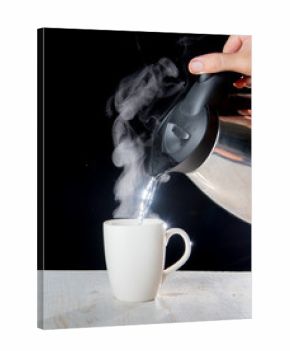 kettle pouring boiling water into a cup with smoke on wood table
