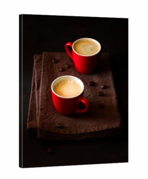 Two red cups of espresso on dark wooden background decorated coffee beans