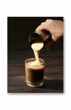 Woman adding condensed milk to coffee at table