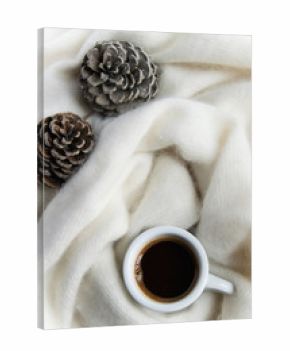 Top view of coffee cup in a cozy warm blanket with pine cones. Autumn-winter concept
