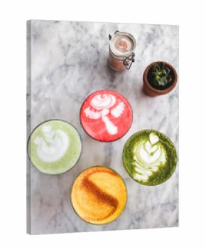 Four different colored latte coffee, style of foam art, natural organic beverages in modern cafe on white marble background