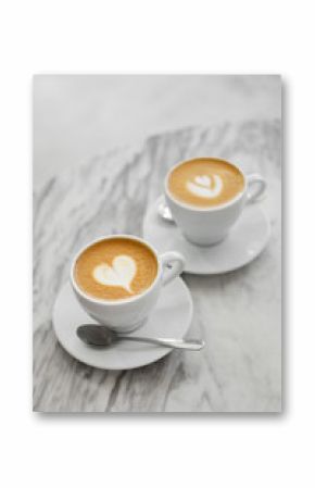 Two cups of coffee with cake art on white background