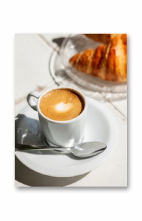 Hot coffee and croissant breakfast in a sunny morning, natural light.