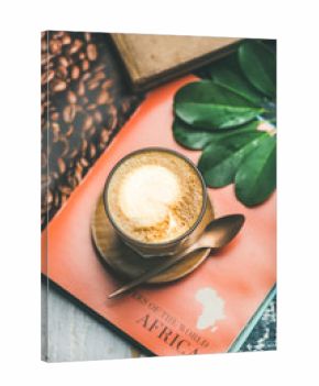 Cappuccino coffee in glass over table with bright magazine background, top view, selective focus, vertical composition