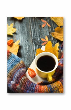 Autumn comfort. Mug of hot coffee with a colorful scarf with colorful autumn leaves on wooden background copy space