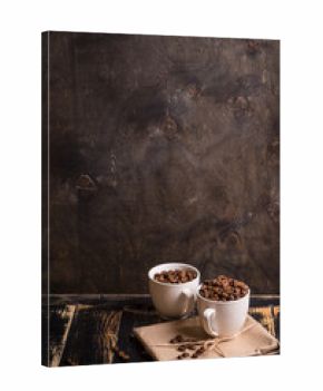 Cup with coffee beans at dark wooden background