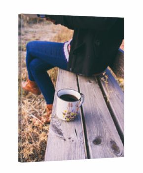 Mujer sentada en un banco en un parque en otoño con su taza de café