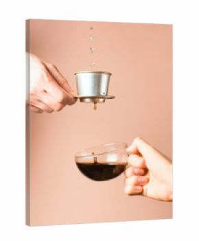 Vietnamese coffee filter in a man's hand pouring coffee into a cup in woman's hand. Alternative brewing