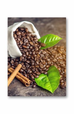 Pile of coffee beans and green leaves in bag on dark background