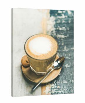 Classic foamy cappuccino coffee in glass over rustic wooden table background