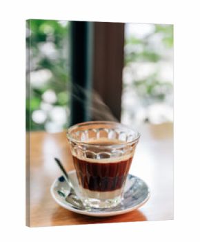 Hot served Vietnamese coffee that can wake you up: Black coffee mix with condense milk in clear glass served on wooden table.